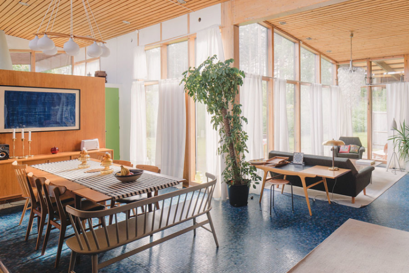 An international house tour in Sweden, showcasing the minimalist wooden framed living room and blue flooring.