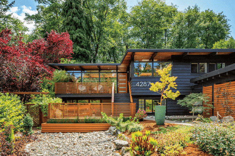 The caviar-painted exterior of this MCM home complete with wooden slats, the surrounding nature, and a zen mid century style.