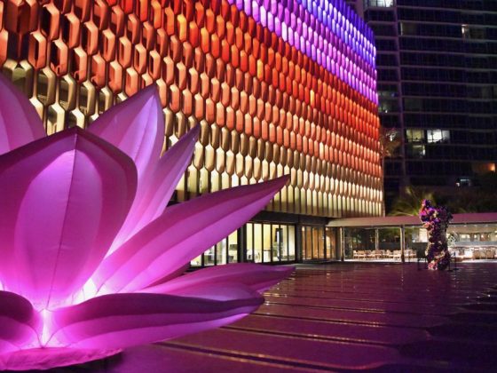 The exterior of Honolulu's IBM Building and lotus sculpture, lit by an array of multi-colored lights.