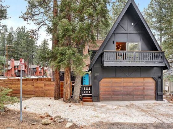 The black exterior of the renovated A-frame cabin, featuring its protruding balcony.