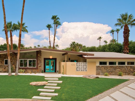 A mid century front yard featuring a blue front door stone walkway.