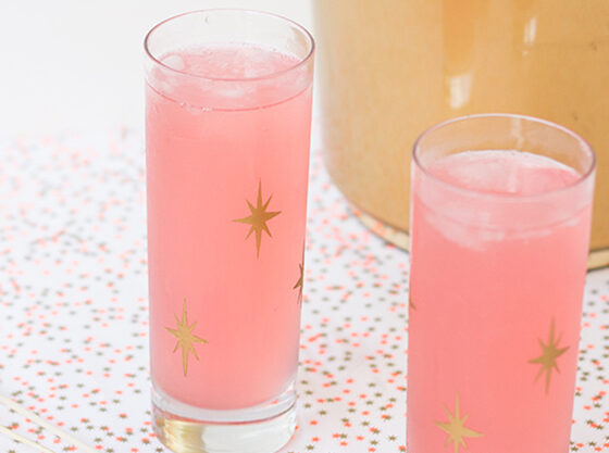 Two glasses with pink lemonade inside and gold starburst pattern on outside