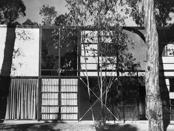 : A black and white photograph of the front of a house. There are about 8 symmetrical rectangle sections showing, each with varying crossbeams and textures