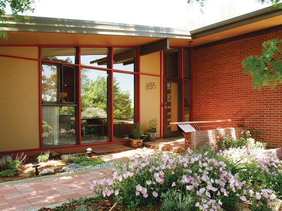 The flowering shrubs in front of this Denver home compliment the warm wood trim of the floor-to-ceiling windows