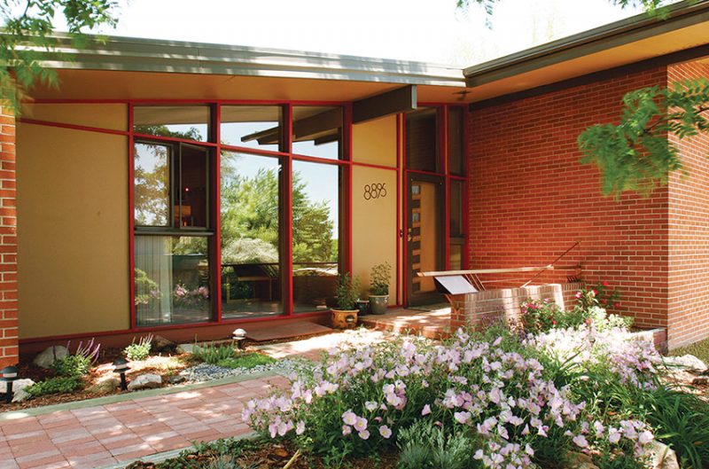 The flowering shrubs in front of this Denver home compliment the warm wood trim of the floor-to-ceiling windows