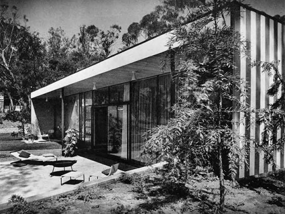 A black and white image of the exterior of the Case Study House #9 with a terrace and lounge seating.