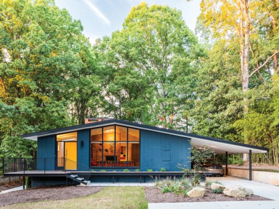 The mid century renovation left the home's exterior with a lovely turquoise coat of paint and warm light coming through the large added windows.