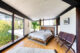 Master bedroom in Mid Century California home with floor to ceiling windows and antique walnut folding church pew