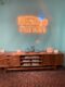 orange neon Atomic Ranch sign hanging on a blue wall
