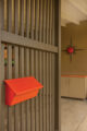 orange metal mailbox and gray wooden slats in entryway
